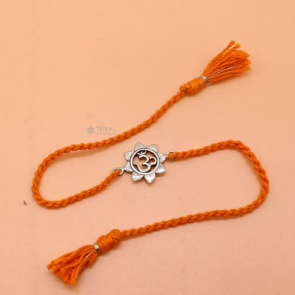 Sterling silver "AUM OM" mantra thread rakhi bracelet with red thread from TRIBAL ORNAMENTS featuring intricate design.