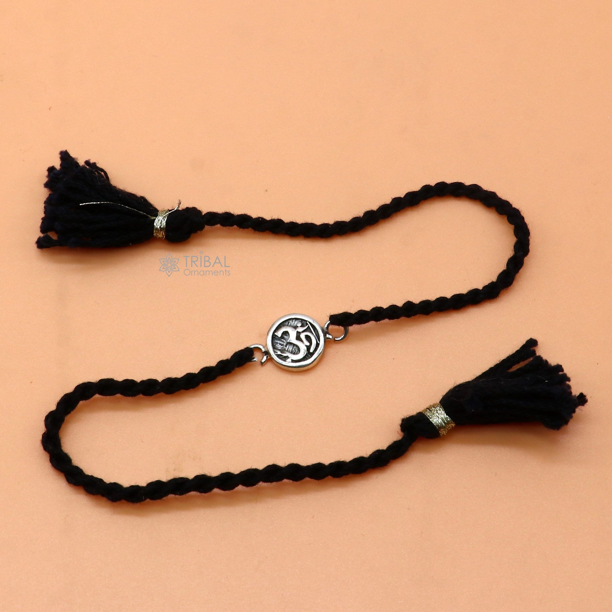 Sterling silver Hindu mantra Aum OM thread rakhi bracelet with red thread and silver pendant, designed by TRIBAL ORNAMENTS.