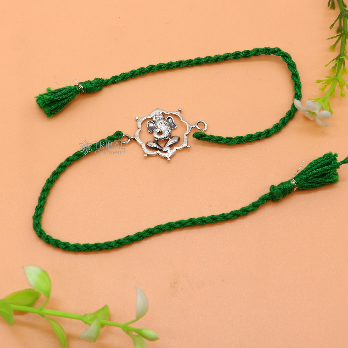 Sterling silver Lord Ganesha pendant on red thread rakhi bracelet by TRIBAL ORNAMENTS, featuring traditional Indian jewelry design.