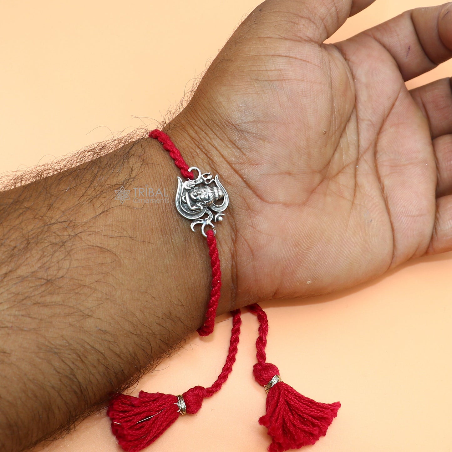Sterling silver Lord Shiva with Aum design thread rakhi bracelet featuring red thread and intricate pendant for religious celebrations.