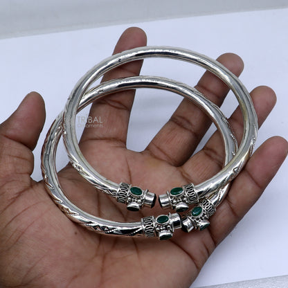 Sterling silver ankle kada bracelet with stylish design and a vibrant green stone, featuring intricate tribal ornament details.