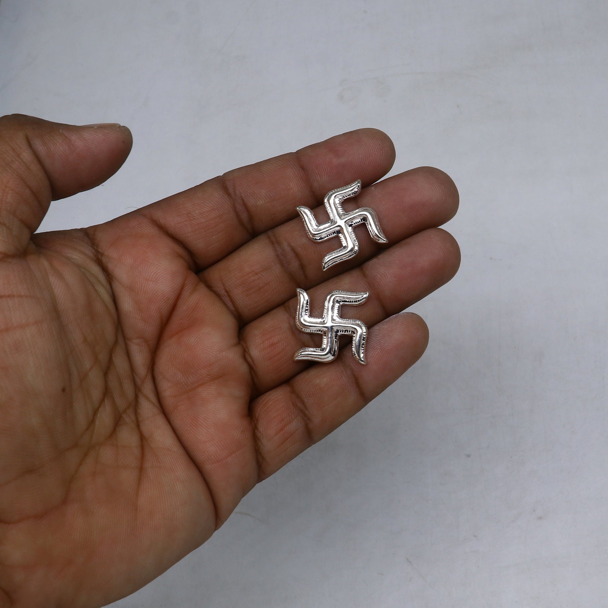 Two 925 sterling silver Swastika symbols from TRIBAL ORNAMENTS Diwali pooja set, traditional decorative jewelry for religious rituals.