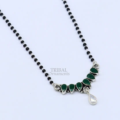 Sterling silver black beads mangalsutra necklace with green stone pendant, floral design, traditional tribal ornament style.