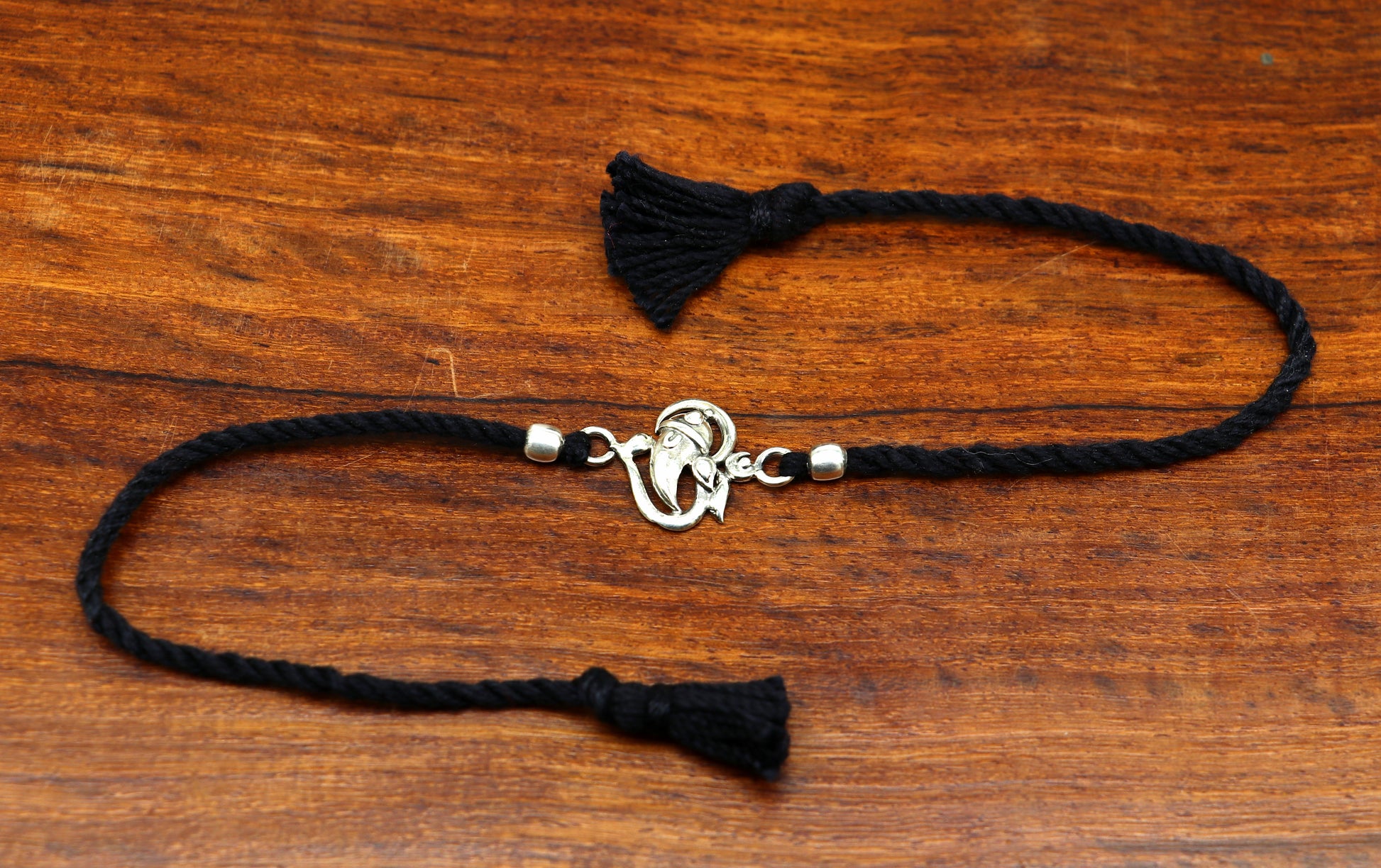 Sterling silver Om Ganesha design bracelet by TRIBAL ORNAMENTS, featuring intricate thread bracelet with spiritual motifs.