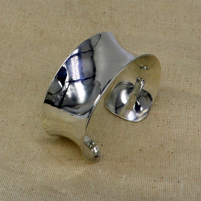 Sterling silver cuff bracelet with a unique curved, shiny design, featuring tribal-inspired elegant jewelry style.