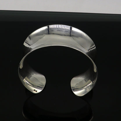 Sterling silver cuff bracelet with a unique curved design, shiny and elegant, by TRIBAL ORNAMENTS, perfect for stylish jewelry collections.