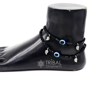 Sterling silver handmade beads with evil eye design on a customized thread ankle bracelet, tribal-inspired foot jewelry.
