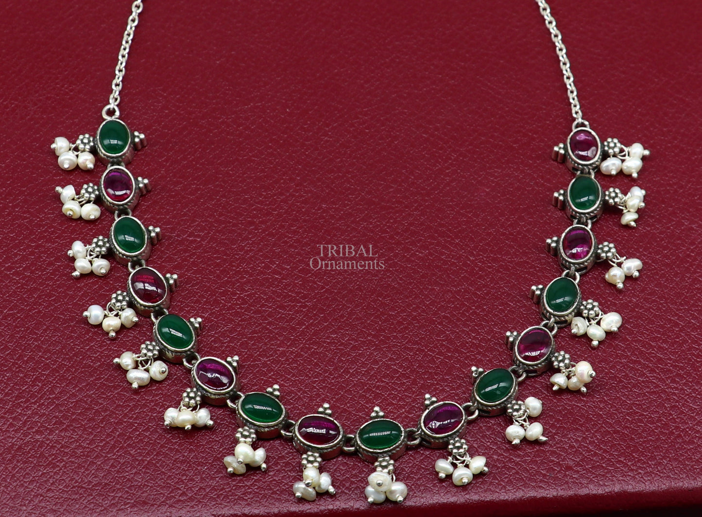 Sterling silver necklace with red and green stones, pearls, and intricate tribal design for wedding or bridal jewelry.