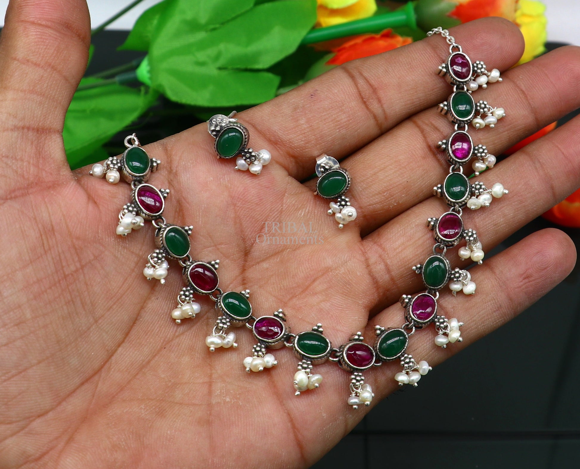 Sterling silver necklace with red and green stones, pearls, and intricate tribal design, styled for wedding or special occasions.