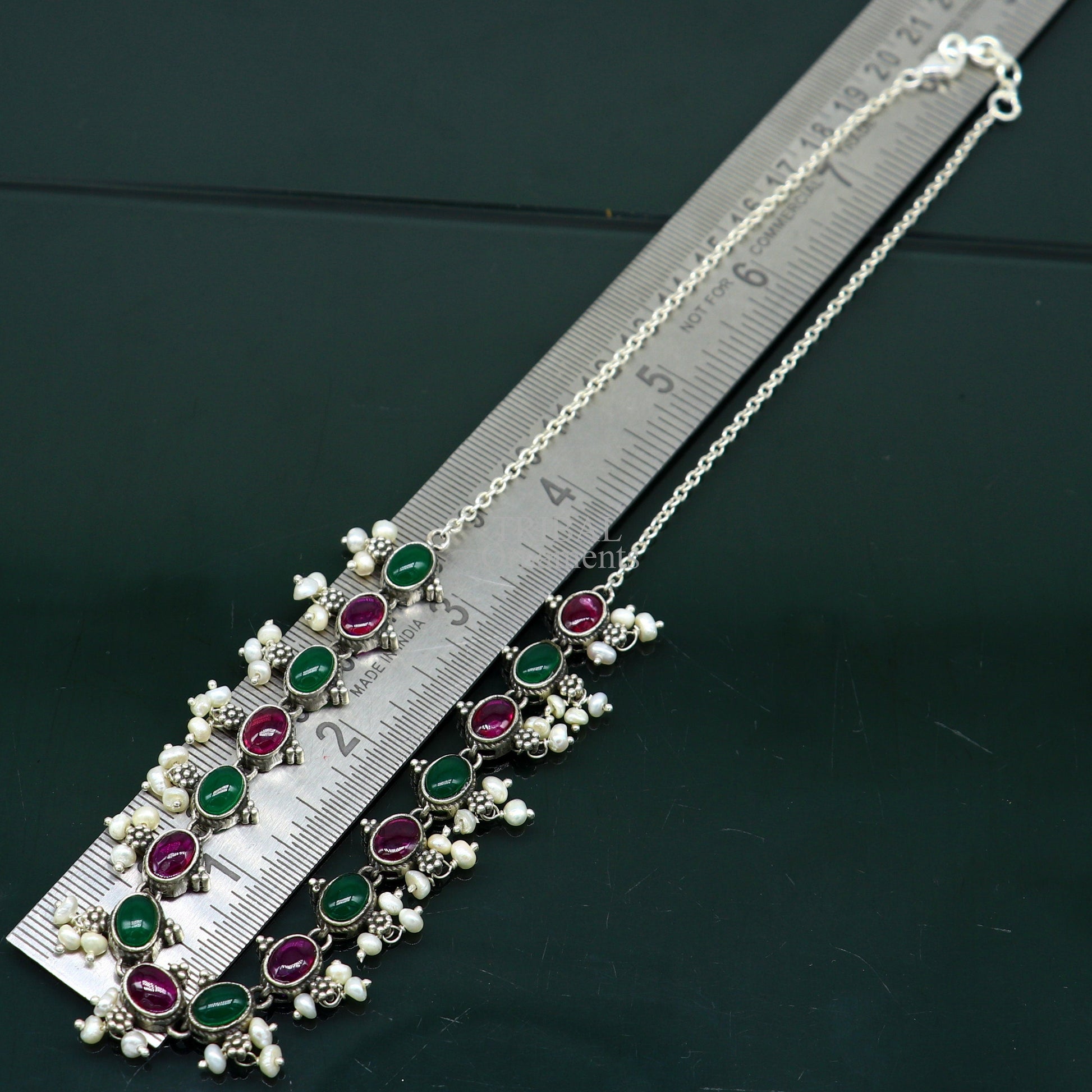 Sterling silver necklace with red and green stones, pearls, and intricate charm design, perfect for wedding or bridal jewelry.