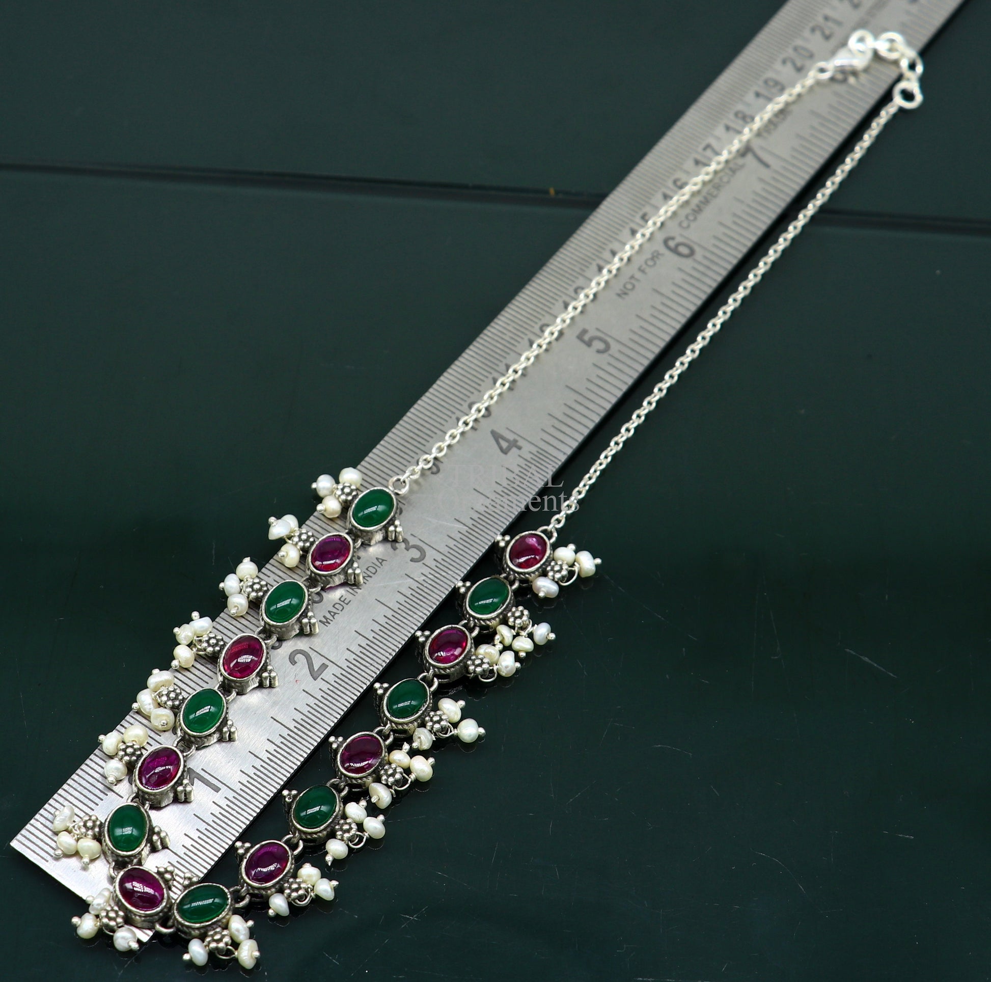Sterling silver necklace with red and green stones, pearls, and charm, designed for weddings and special occasions.