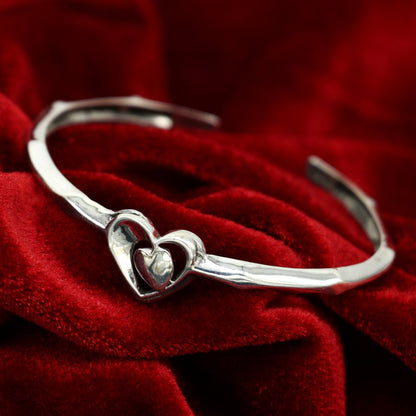 Sterling silver heart design bangle cuff bracelet by Tribal Ornaments, adjustable handmade jewelry with intricate heart details.