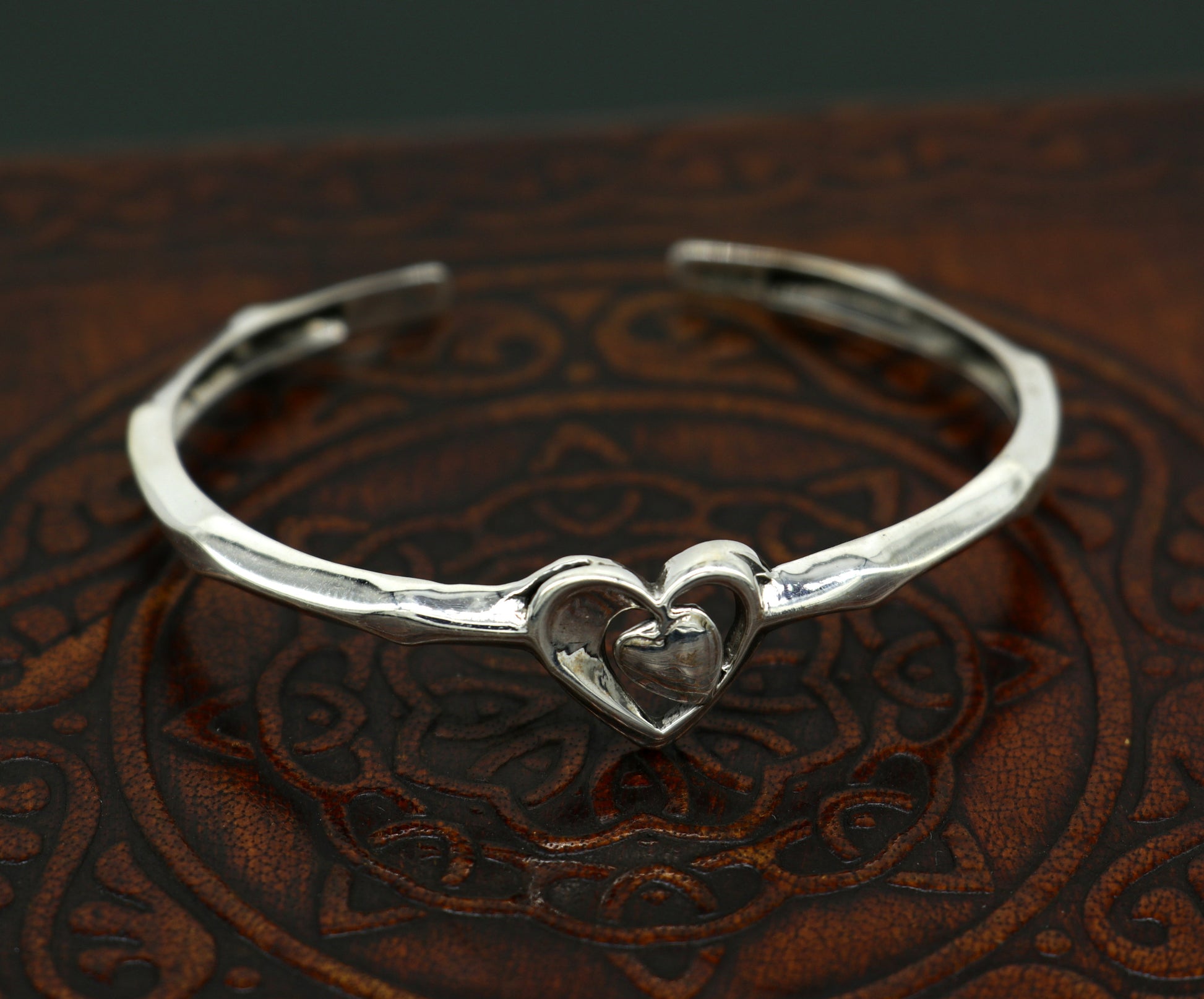 Sterling silver heart design bangle cuff bracelet by Tribal Ornaments, adjustable handmade silver jewelry with intricate heart pattern.