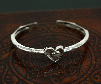 Sterling silver heart design bangle cuff bracelet by Tribal Ornaments, adjustable handmade silver jewelry with intricate heart pattern.
