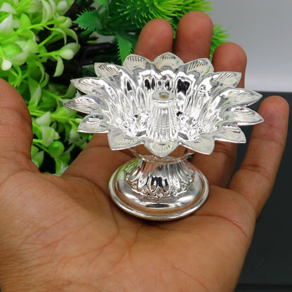 Handmade silver flower-shaped oil lamp by TRIBAL ORNAMENTS, featuring temple utensils, diya, and decorative silver vessels.