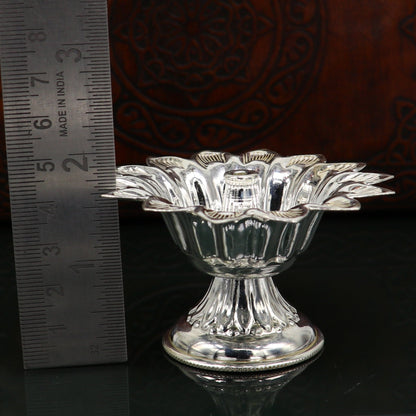 Handmade silver flower-shaped oil lamp by TRIBAL ORNAMENTS, traditional temple diya with decorative vessels and silver art.