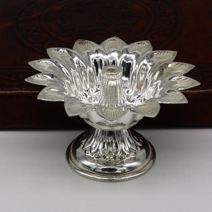 Handmade silver flower-shaped oil lamp with intricate temple utensils and decorative vessels, showcasing tribal ornaments craftsmanship.
