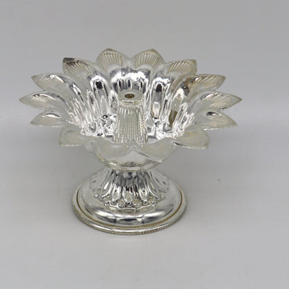 Handmade silver flower-shaped oil lamp with intricate detailing, part of temple utensils and decorative silver diya collection.