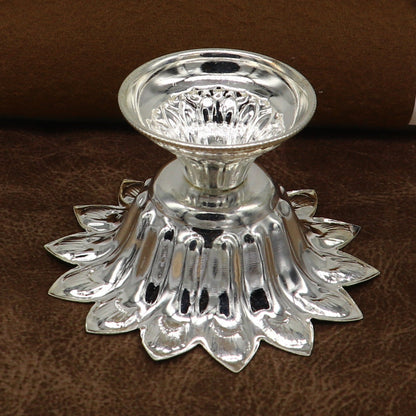Handmade silver flower-shaped oil lamp by TRIBAL ORNAMENTS, featuring temple utensils and decorative silver diya vessels.