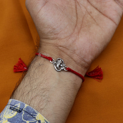 Handmade 925 sterling silver Ganesha, Shiva Lingam, Sai Baba idols woven into a unique thread rakhi bracelet by Tribal Ornaments.
