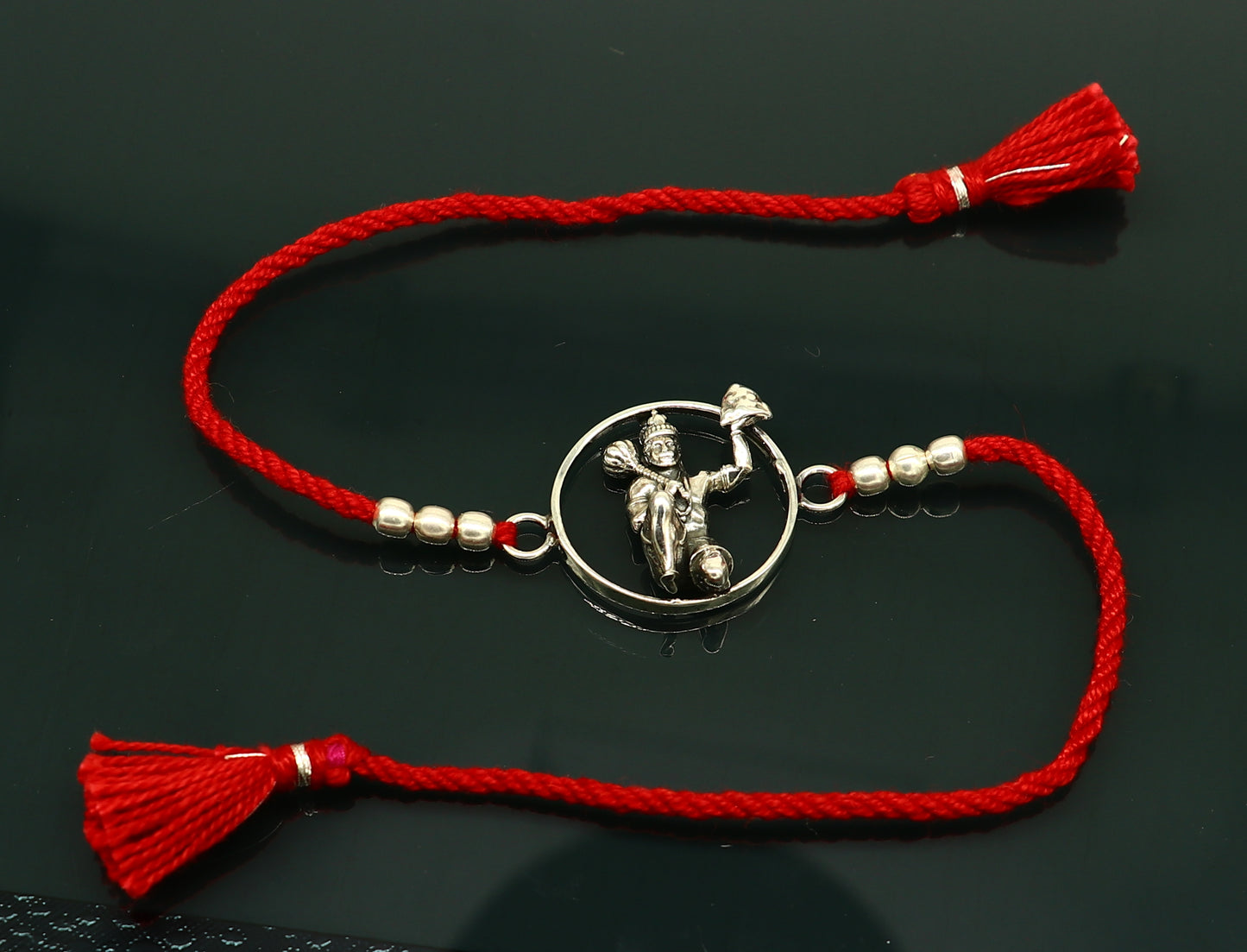 925 sterling silver Hanuman design bracelet with red thread Rakhi, crafted by Tribal Ornaments, featuring intricate idol and bracelet details.