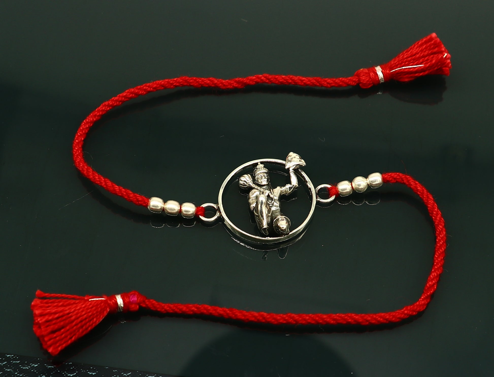 925 sterling silver Hanuman design bracelet with red thread Rakhi, crafted by Tribal Ornaments, featuring intricate idol and bracelet details.