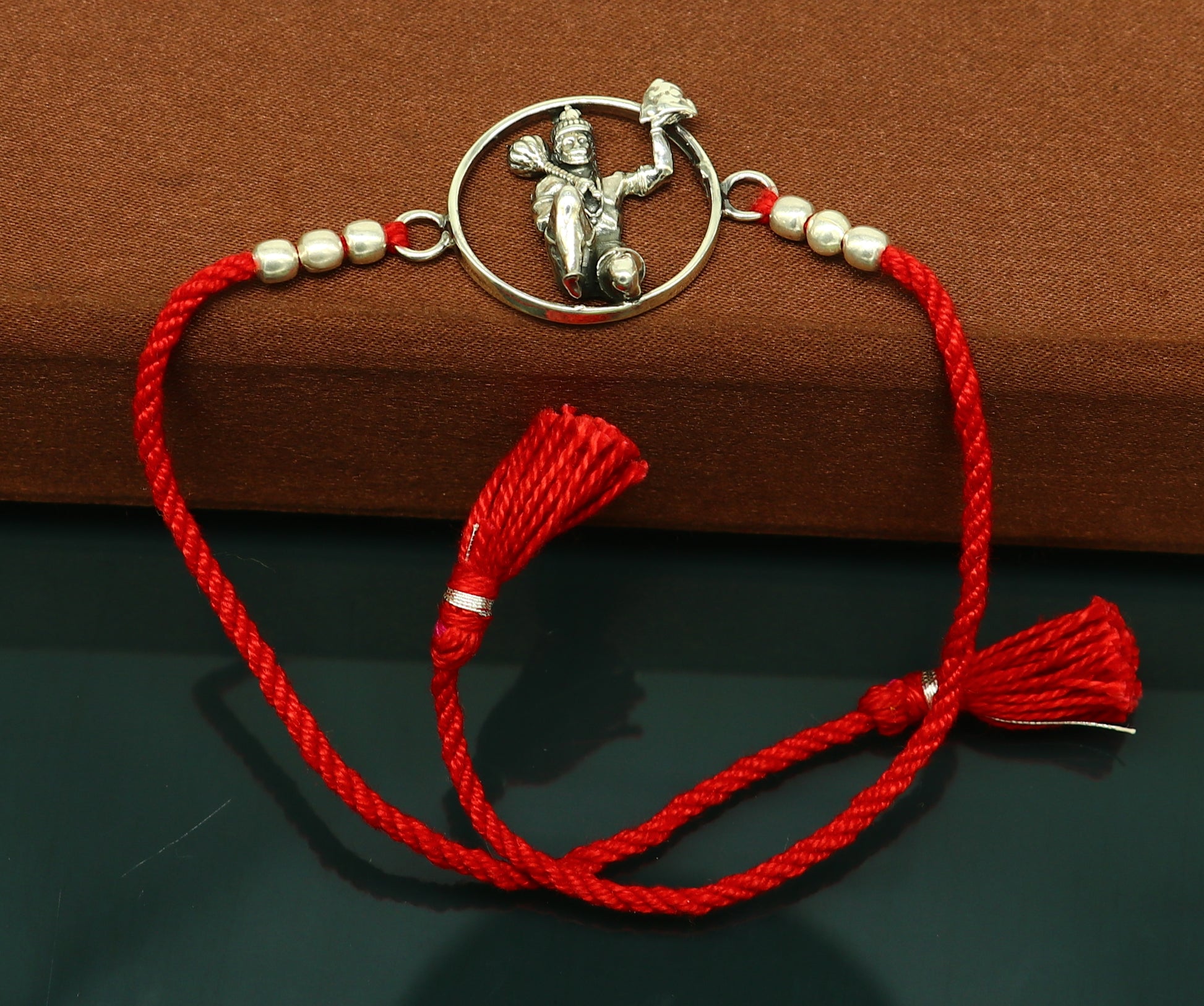 Sterling silver Hanuman bracelet with red thread rakhi from Tribal Ornaments, featuring a detailed idol design.