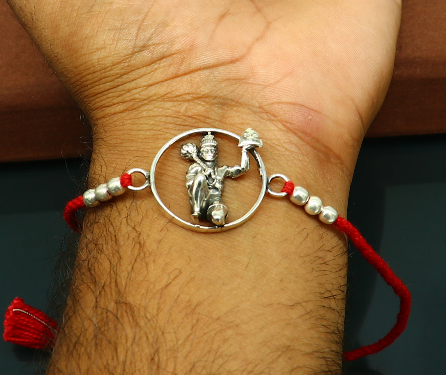 Sterling silver Hanuman design bracelet with red thread rakhi by Tribal Ornaments, featuring intricate idol motif and traditional style.
