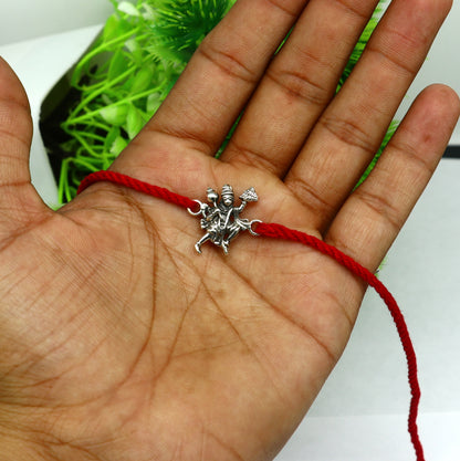 Sterling silver Flying Hanuman idol bracelet with red thread Rakhi from Tribal Ornaments, featuring intricate deity design.