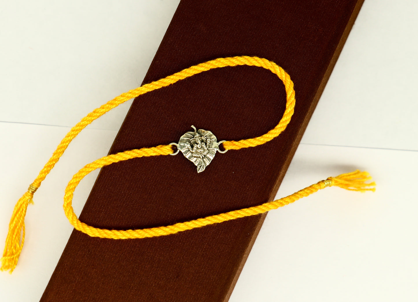 925 sterling silver Ganesha bracelet with yellow thread rakhi, featuring intricate tribal design from TRIBAL ORNAMENTS.