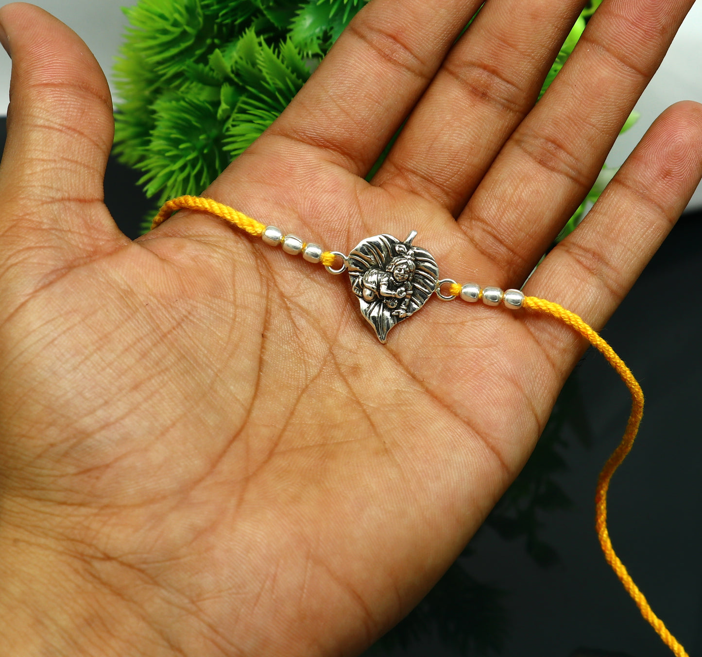 Sterling silver Krishna design Rakhi bracelet with yellow thread, featuring Lord Krishna and Laddu Gopal motifs, by TRIBAL ORNAMENTS.