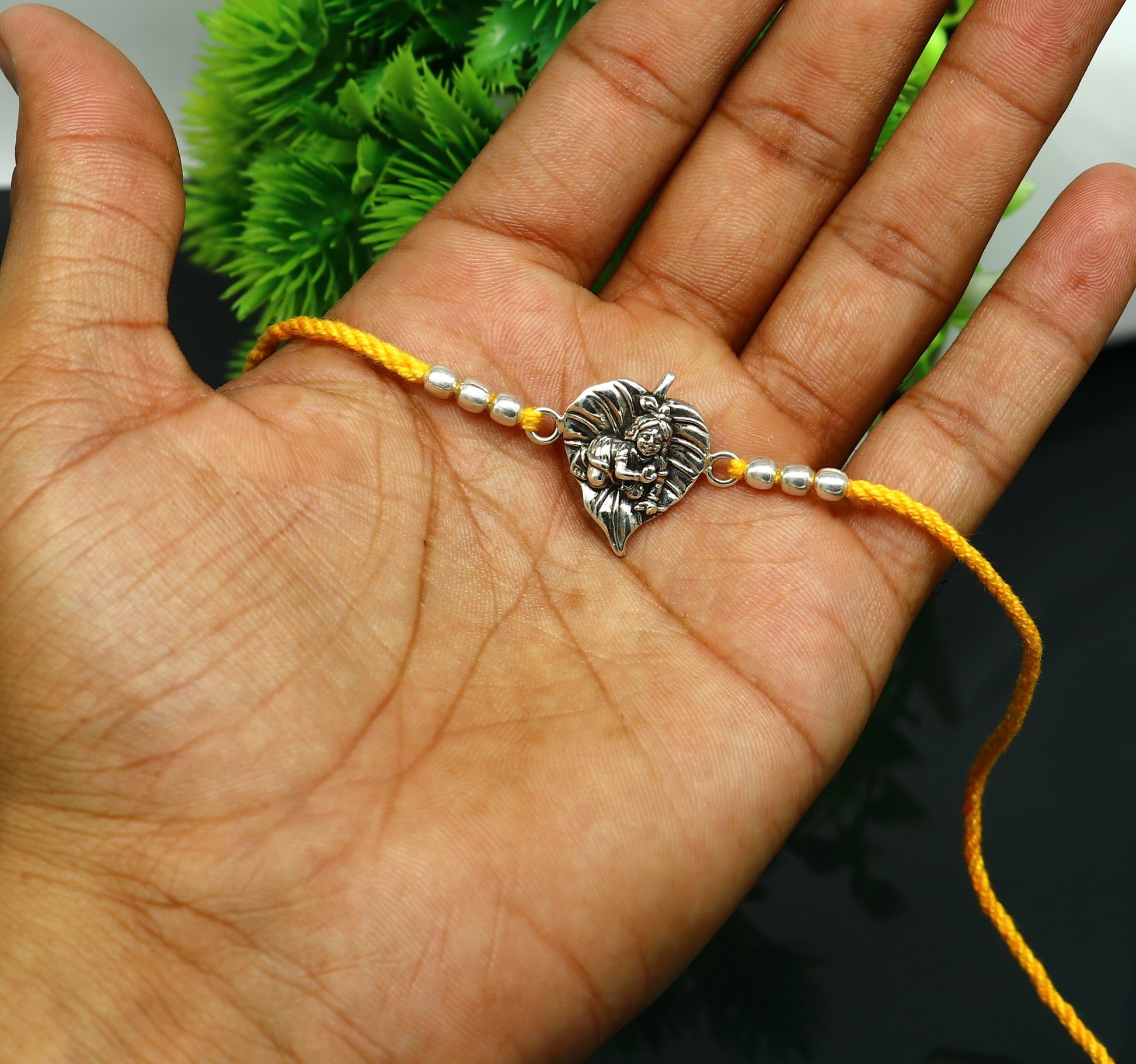 Sterling silver Krishna design Rakhi bracelet with yellow thread, featuring Lord Krishna and Laddu Gopal motifs, by TRIBAL ORNAMENTS.