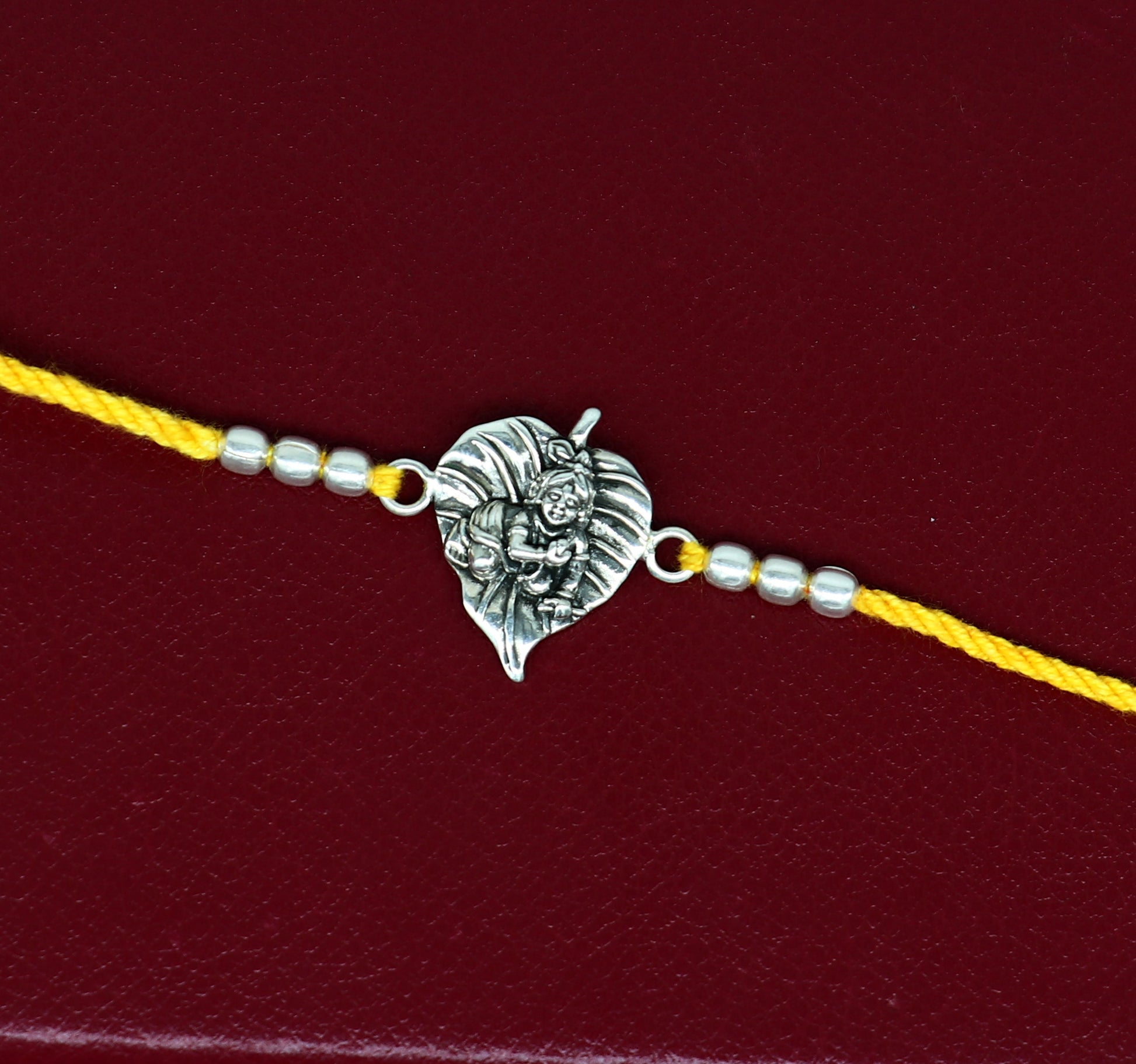 925 sterling silver Krishna design bracelet with yellow thread Rakhi, featuring Lord Krishna and Laddu Gopal motifs by TRIBAL ORNAMENTS.