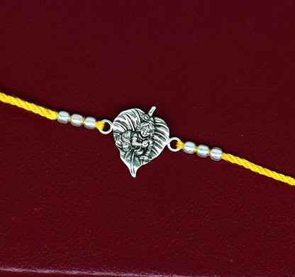 925 sterling silver Krishna design bracelet with yellow thread Rakhi, featuring Lord Krishna and Laddu Gopal motifs by TRIBAL ORNAMENTS.