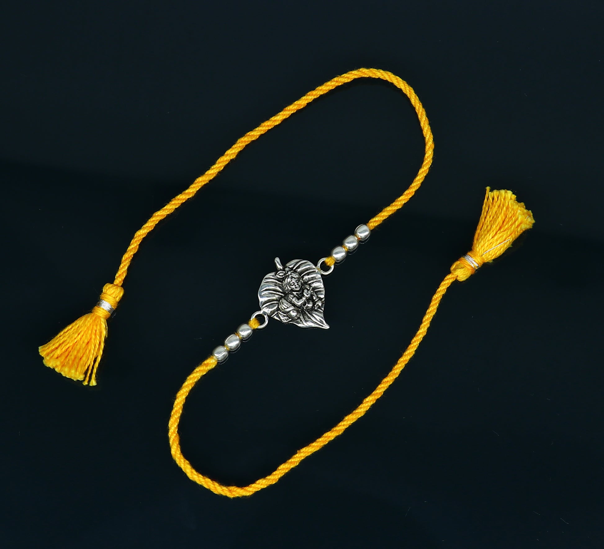 925 sterling silver Krishna design bracelet with yellow thread rakhi, featuring Lord Krishna and traditional decorative elements.