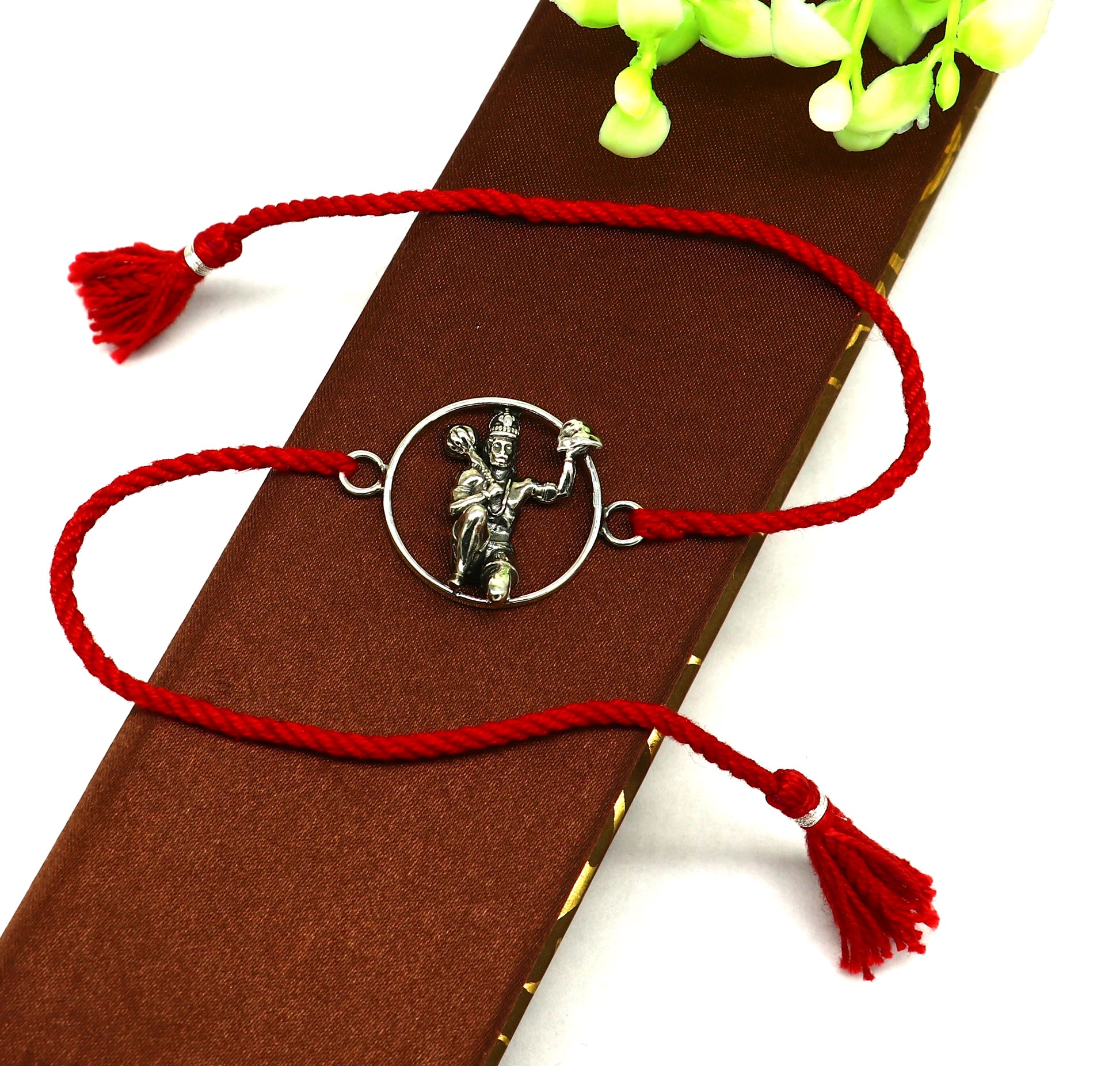 Sterling silver Hanuman idol bracelet with red thread rakhi, showcasing intricate tribal design and vibrant red thread.