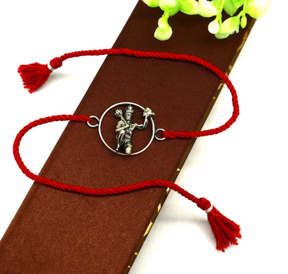 Sterling silver Hanuman idol bracelet with red thread rakhi, showcasing intricate tribal design and vibrant red thread.