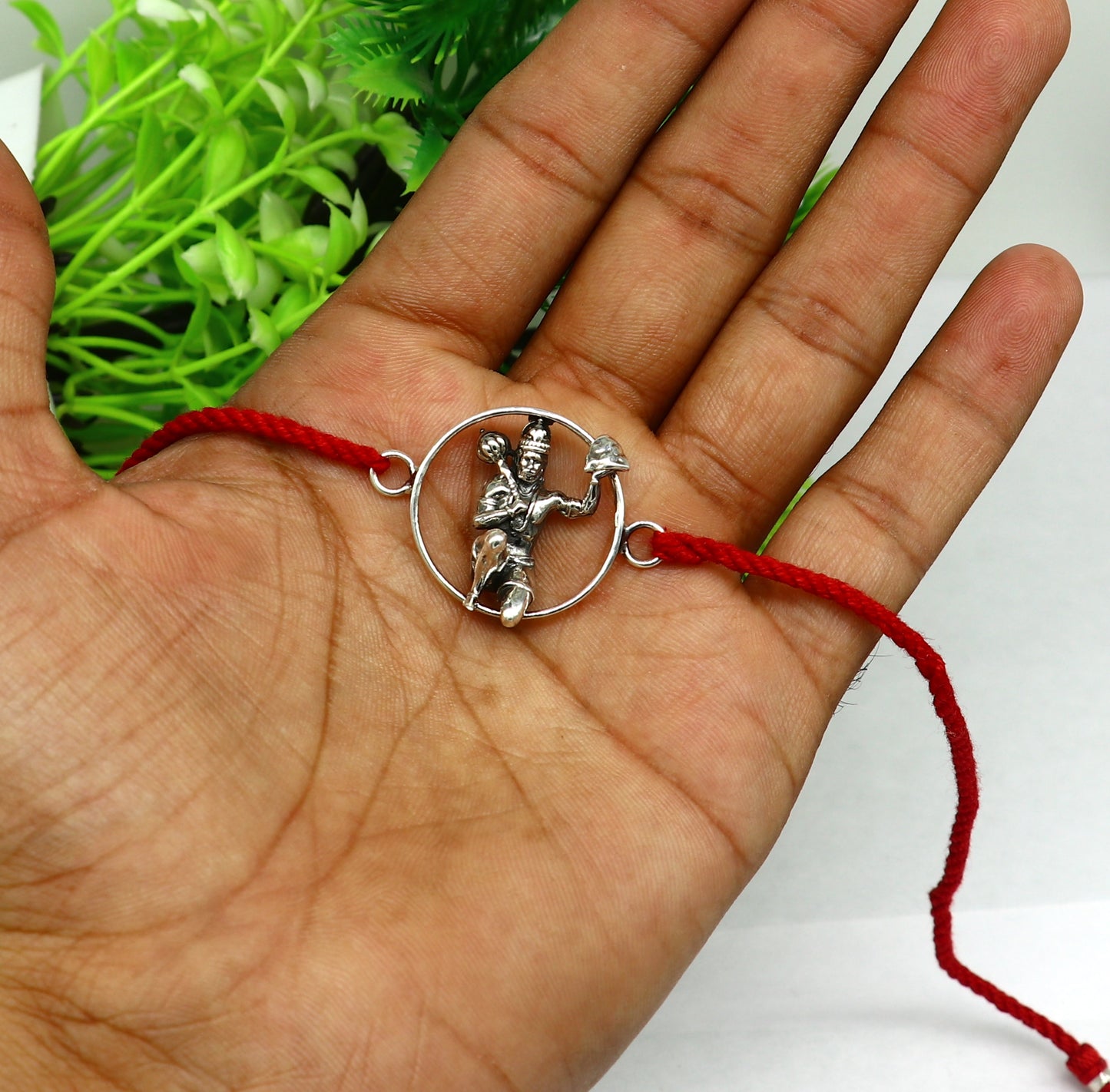 Sterling silver Hanuman design bracelet with red thread rakhi, featuring intricate tribal ornament details for traditional celebration.