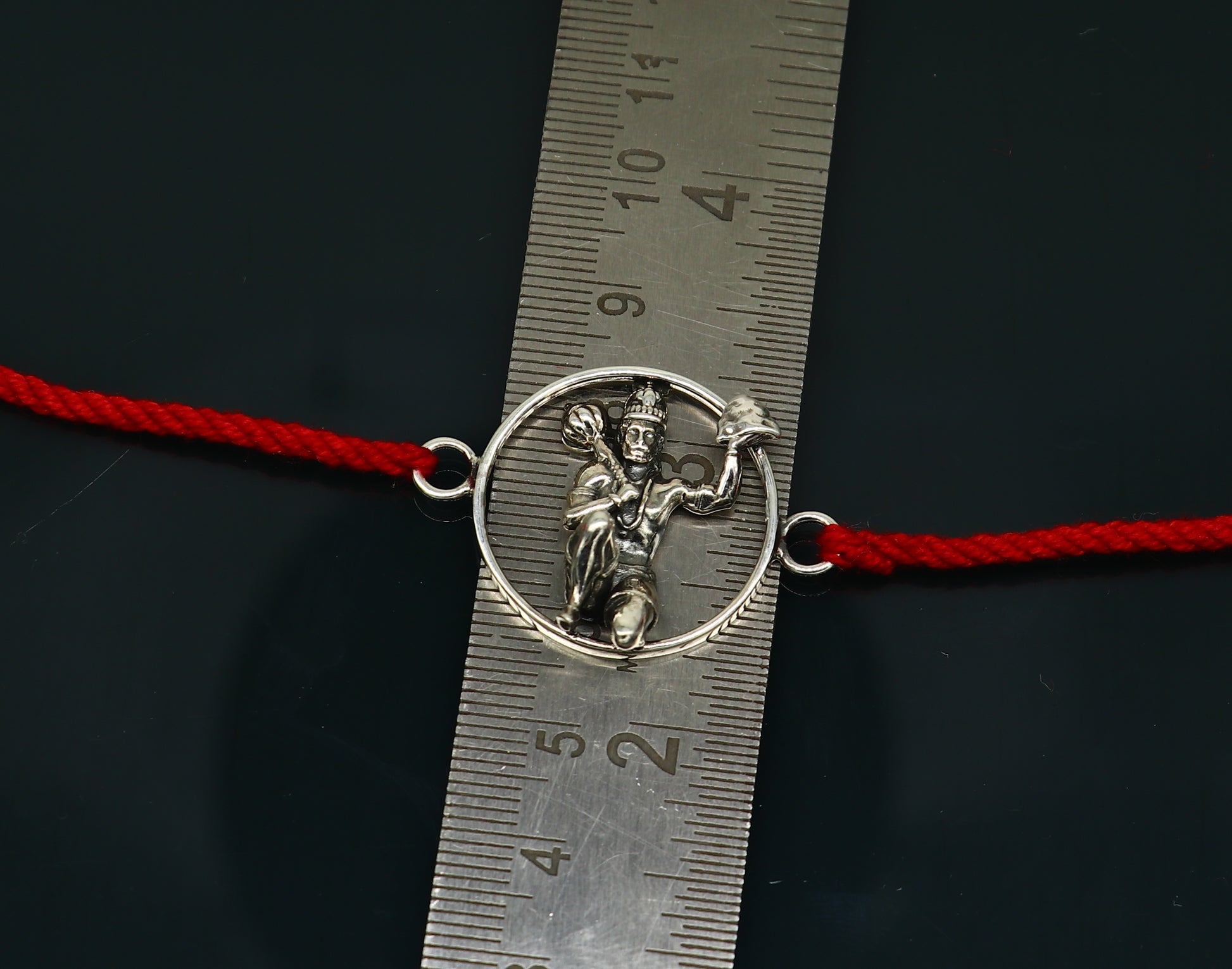 Sterling silver Hanuman idol bracelet with red thread rakhi, featuring intricate tribal design and craftsmanship by Tribal Ornaments.