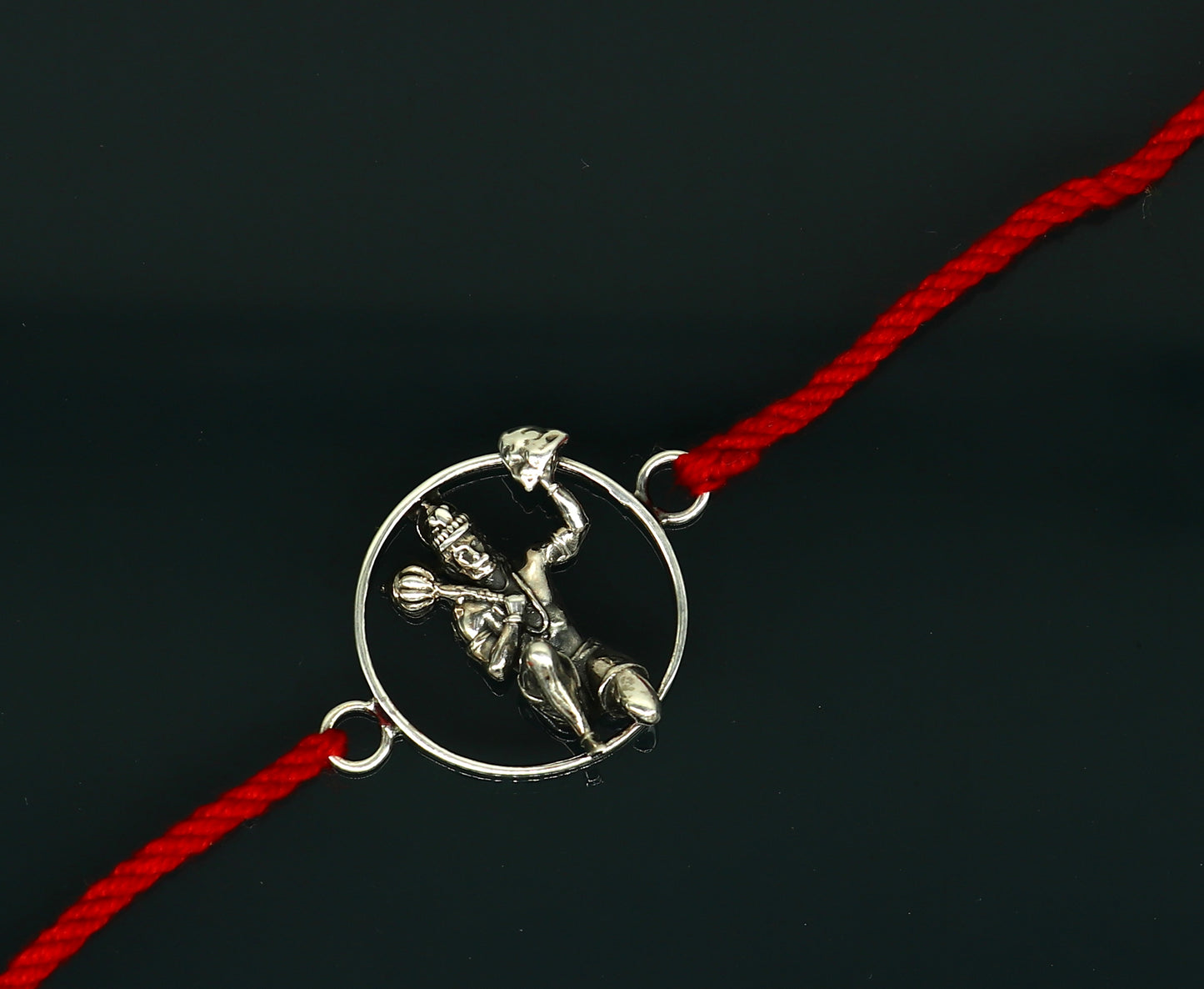 Sterling silver Hanuman idol bracelet with red thread rakhi, featuring intricate tribal ornament design.