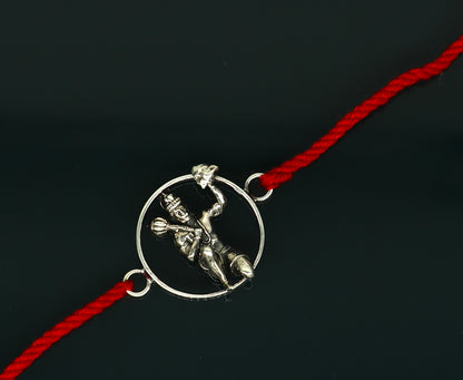 Sterling silver Hanuman idol bracelet with red thread rakhi, featuring intricate tribal ornament design.