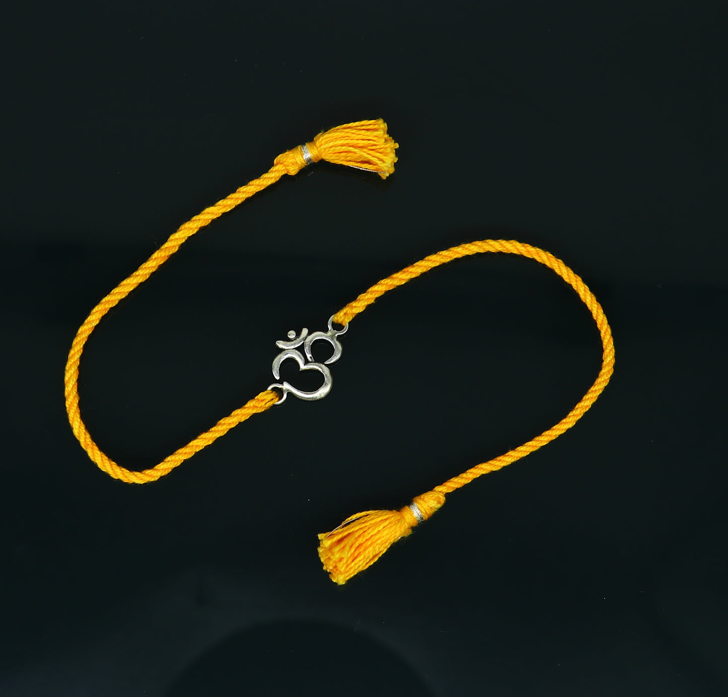 925 sterling silver OM design bracelet with yellow thread rakhi, handcrafted by TRIBAL ORNAMENTS featuring custom jewelry style.