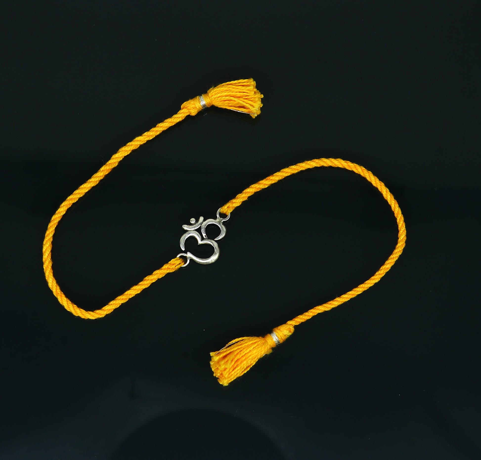 925 sterling silver OM design bracelet with yellow thread rakhi, handcrafted by TRIBAL ORNAMENTS featuring custom jewelry style.