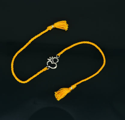 925 sterling silver OM design bracelet with yellow thread rakhi, handcrafted by TRIBAL ORNAMENTS featuring custom jewelry style.