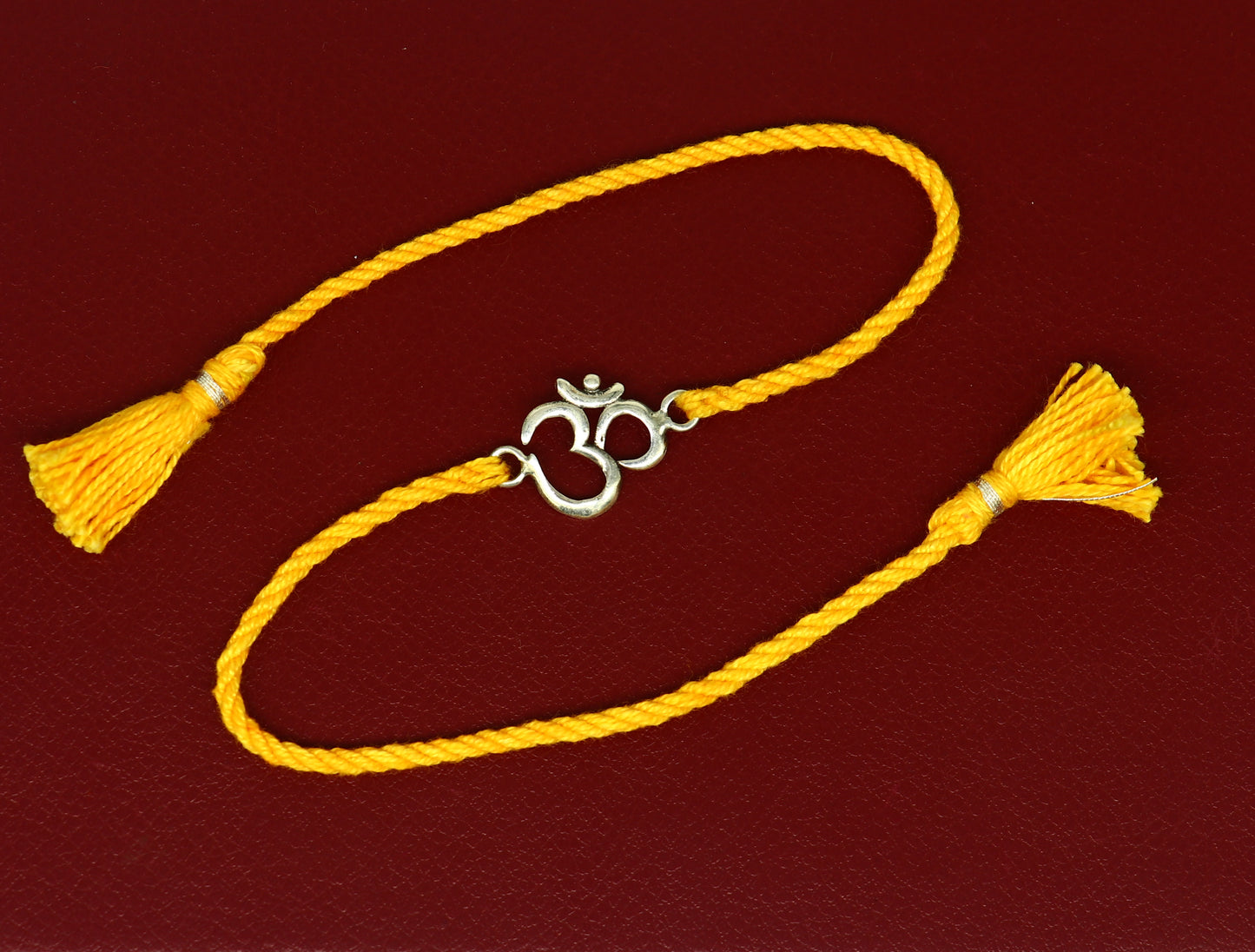 925 silver OM design bracelet with yellow thread rakhi, featuring custom sterling silver craftsmanship and intricate Aum motif.