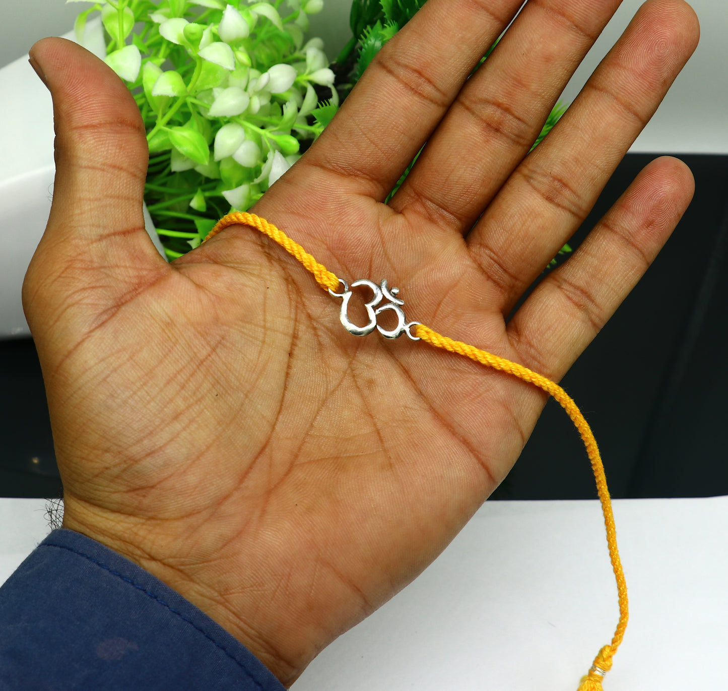 Sterling silver OM design bracelet with yellow thread, custom Rakhi from Tribal Ornaments featuring intricate silver craftsmanship.