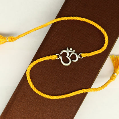 925 sterling silver OM design bracelet with vibrant yellow thread, custom rakhi by TRIBAL ORNAMENTS featuring intricate silver and red accents.
